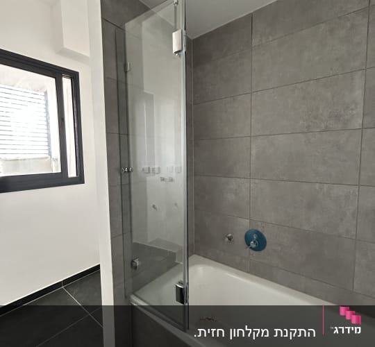 אמבטיה עם דלת זכוכית ומקלחת קיר
